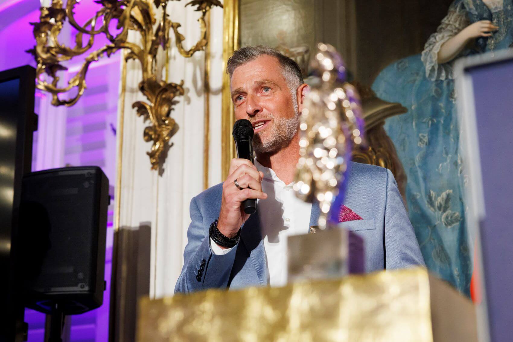 Ein Mann in hellblauem Sakko und weißem Hemd mit einem Mikrofon in der Hand bei seiner Dankesrede bei der TIROLERIN Award-Verleihung